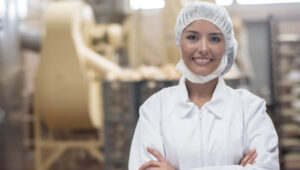 Latin American woman working at a food factory looking at the camera and smiling